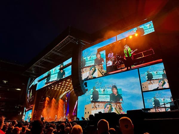 Rolling Stones playing on stage after an extensive av setup including multiple large screen displays, lighting, and smoke effects.